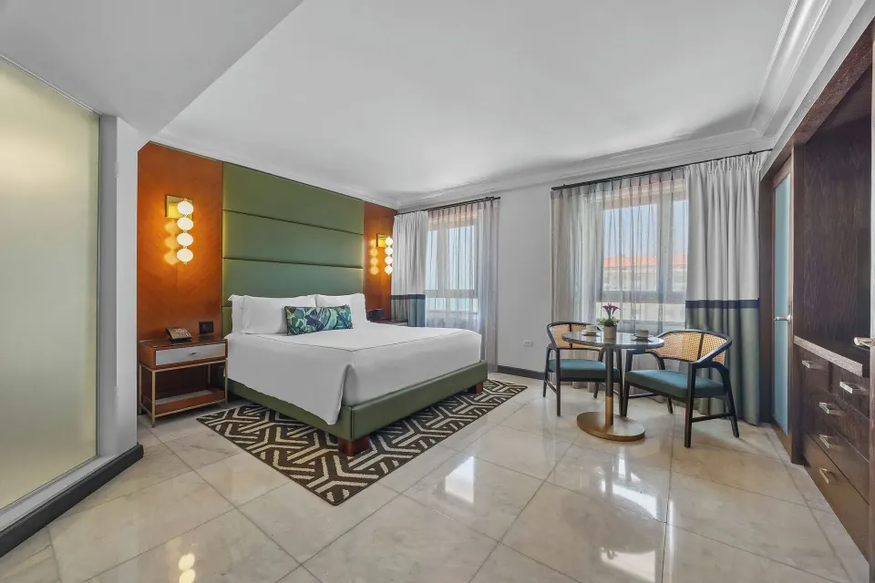 Spacious king guest room with sitting table and two windows at Condado Vanderbilt Hotel.