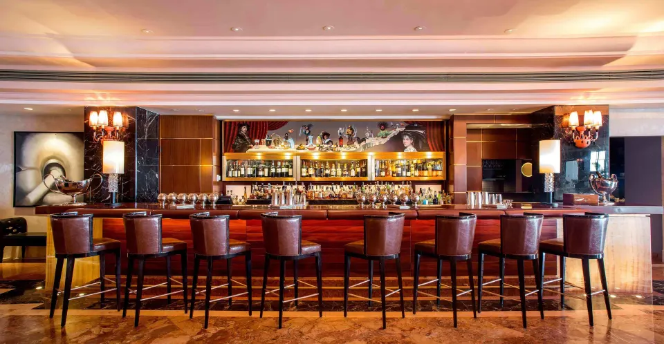 Indoor bar with tall stools and backlit bottles at Condado Vanderbilt Hotel.