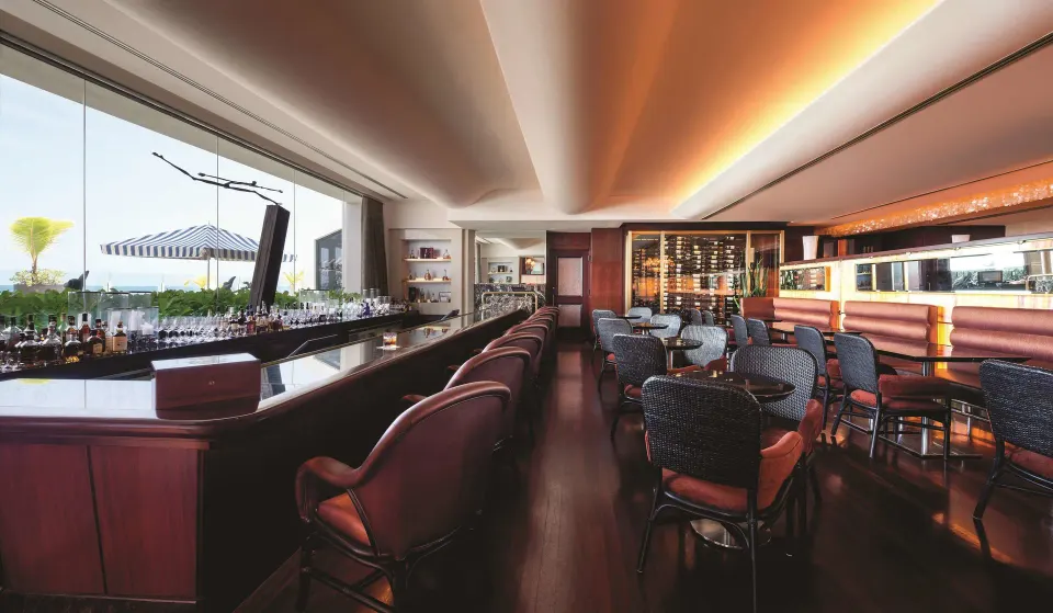 Bar and lounge seating with ocean-view windows at Condado Vanderbilt Hotel.