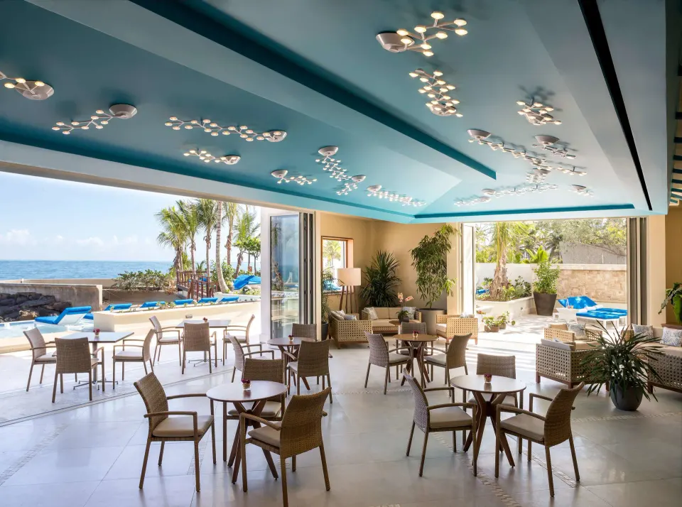 Open-air lounge seating beside the pool and ocean at Condado Vanderbilt Hotel.