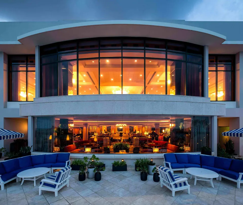 Outdoor terrace seating outside a warmly lit lounge at Condado Vanderbilt Hotel.