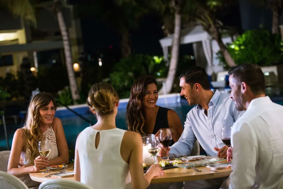 Guests dining outdoors by the pool at night at Condado Vanderbilt Hotel.