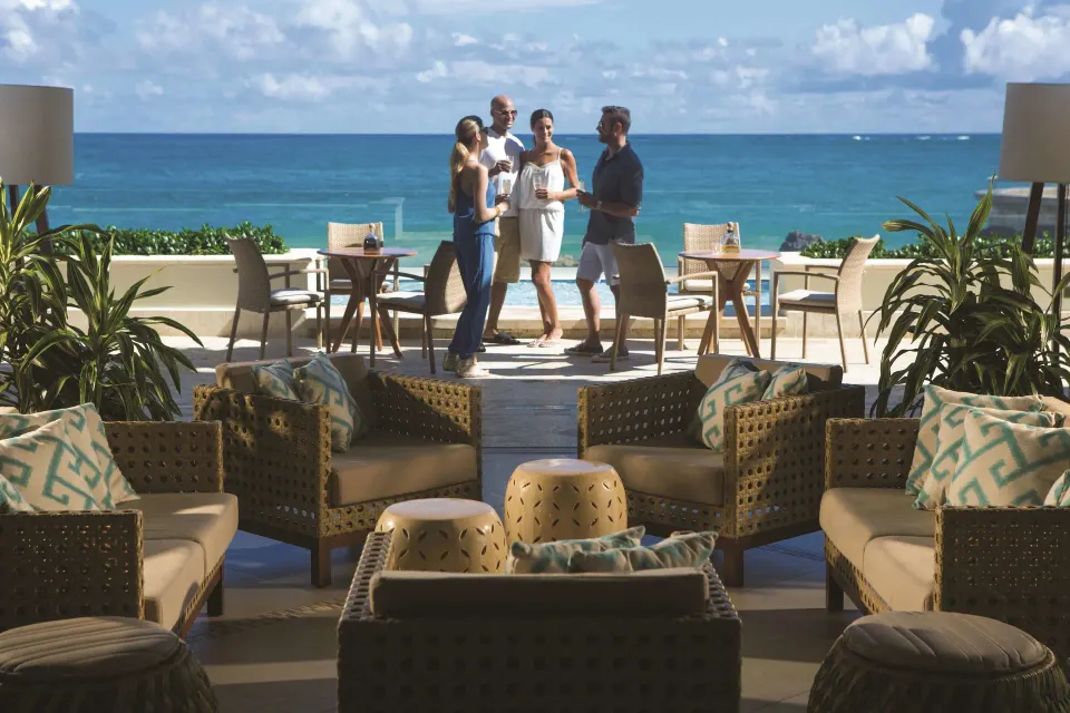 Seaside lounge seating with guests near the ocean at Condado Vanderbilt Hotel.