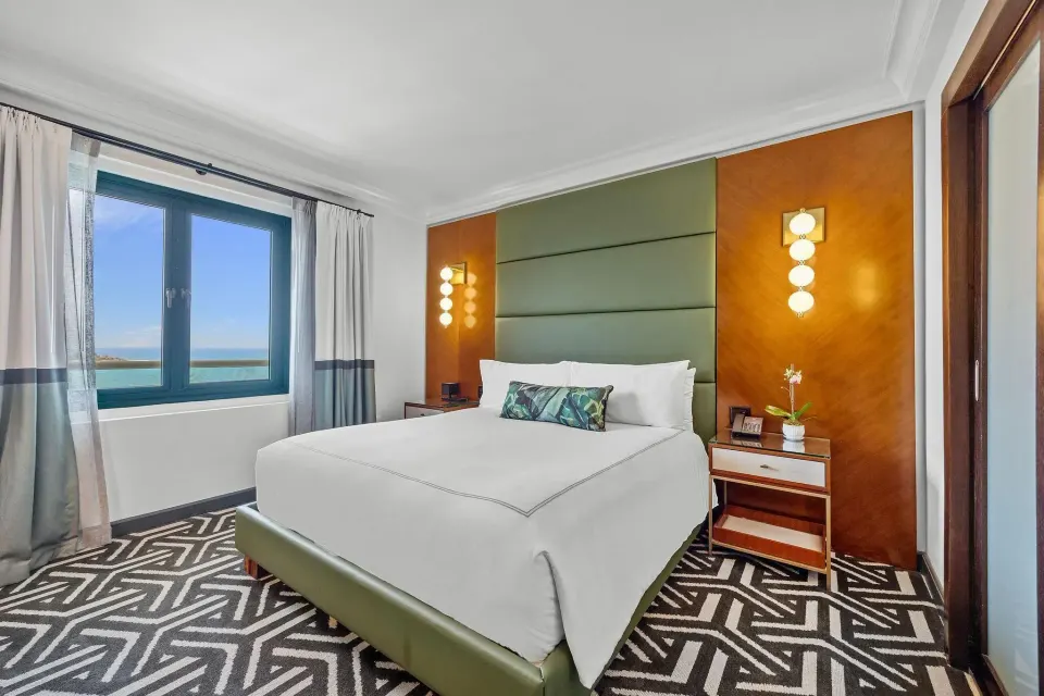Biltmore Ocean View One-Bedroom Suite king bed with ocean-facing window at Condado Vanderbilt Hotel.