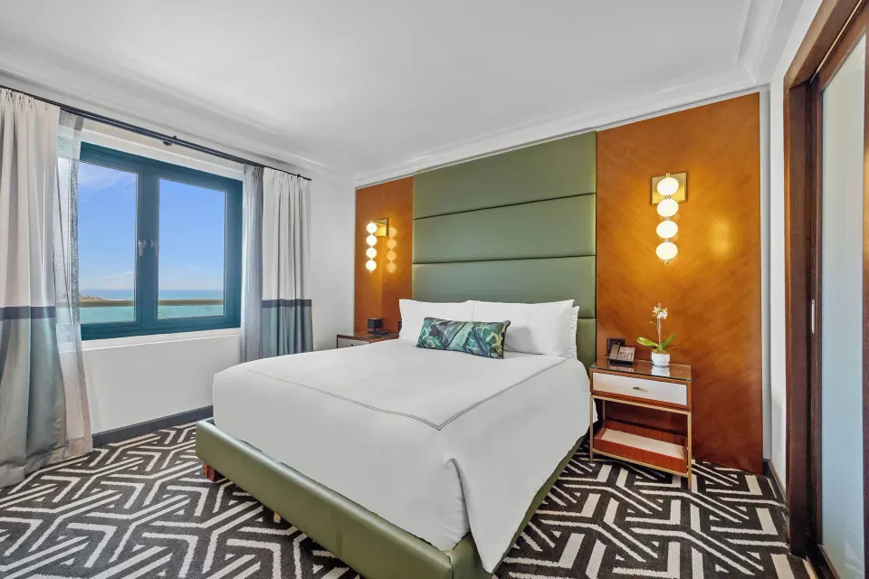 Biltmore Ocean View One-Bedroom Suite king bed and ocean window at Condado Vanderbilt Hotel.