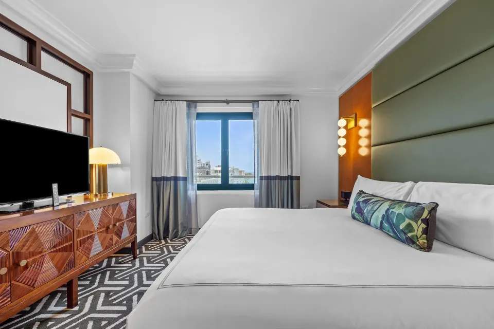 Biltmore Ocean View One-Bedroom Suite king bed, TV console, and window at Condado Vanderbilt Hotel.