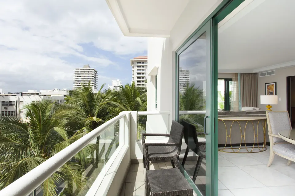 Balcony of the Commodore City View One-Bedroom Suite at Condado Vanderbilt Hotel overlooking palms and city buildings.