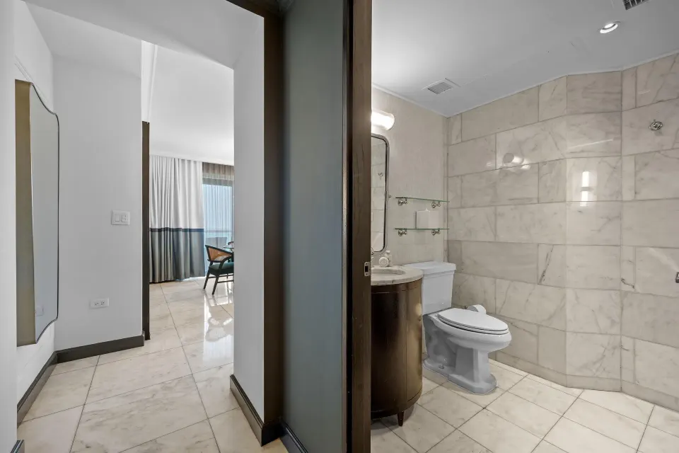 Marble bathroom with sink and toilet in the Commodore City View Suite at Condado Vanderbilt Hotel.