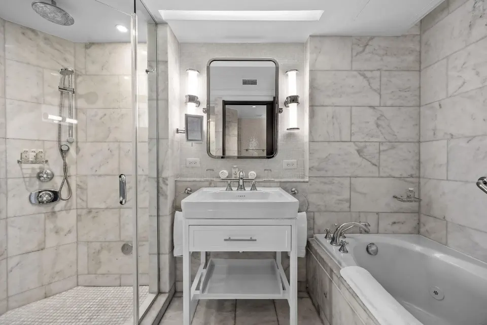 Bathroom in the Commodore City View One-Bedroom Suite at Condado Vanderbilt Hotel with shower, vanity and tub.