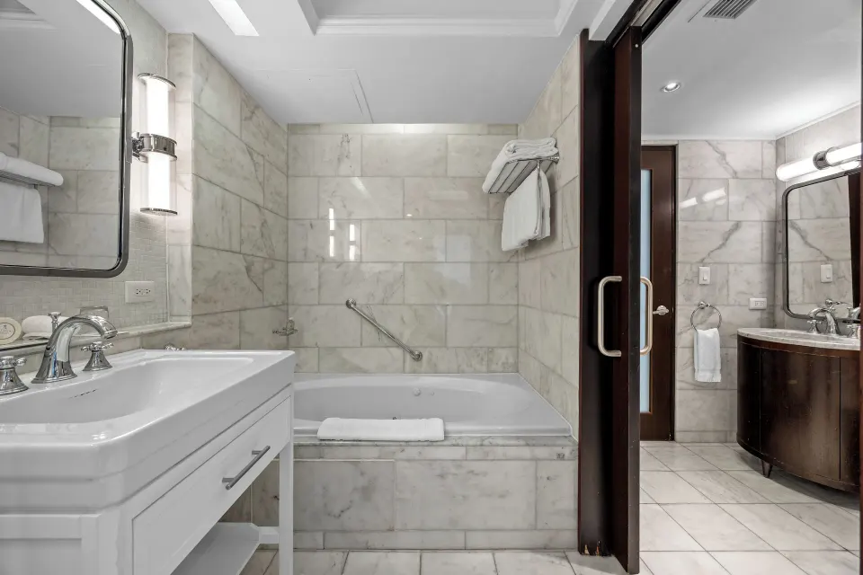 Tub area of the Commodore City View One-Bedroom Suite bathroom at Condado Vanderbilt Hotel with marble walls.