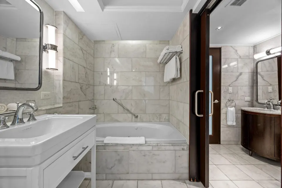 Marble bathroom in the Commodore City View One-Bedroom Suite at Condado Vanderbilt Hotel with tub and double vanity.