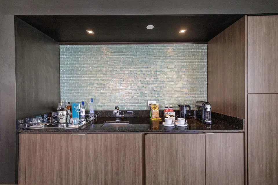 Wet bar in the Commodore City View One-Bedroom Suite at Condado Vanderbilt Hotel with sink, glasses and coffee setup.