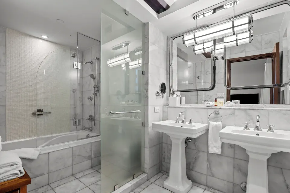 Bathroom with twin pedestal sinks and glass shower in a Heritage King Room at Condado Vanderbilt Hotel.