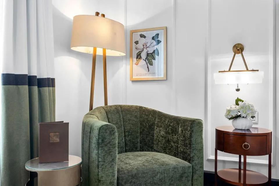 Green lounge chair and side table in a Heritage King Room at Condado Vanderbilt Hotel.