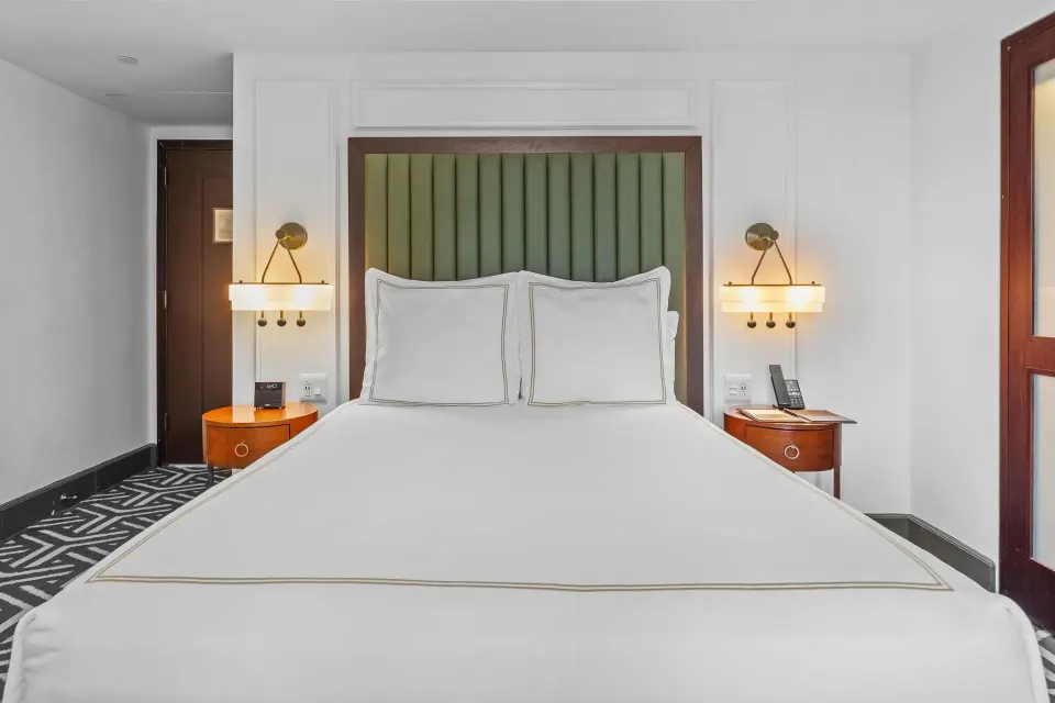 Heritage Queen Room bed with green headboard and matching bedside lamps at Condado Vanderbilt Hotel.