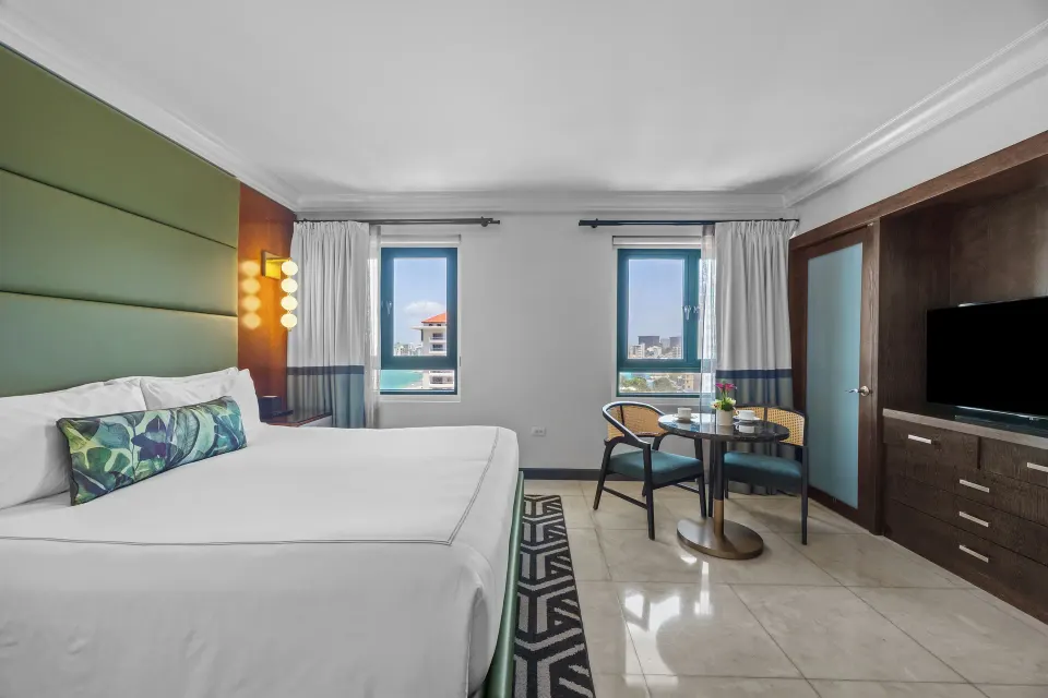 Ocean View Tower King Room with king bed, TV cabinet, and window table at Condado Vanderbilt Hotel.