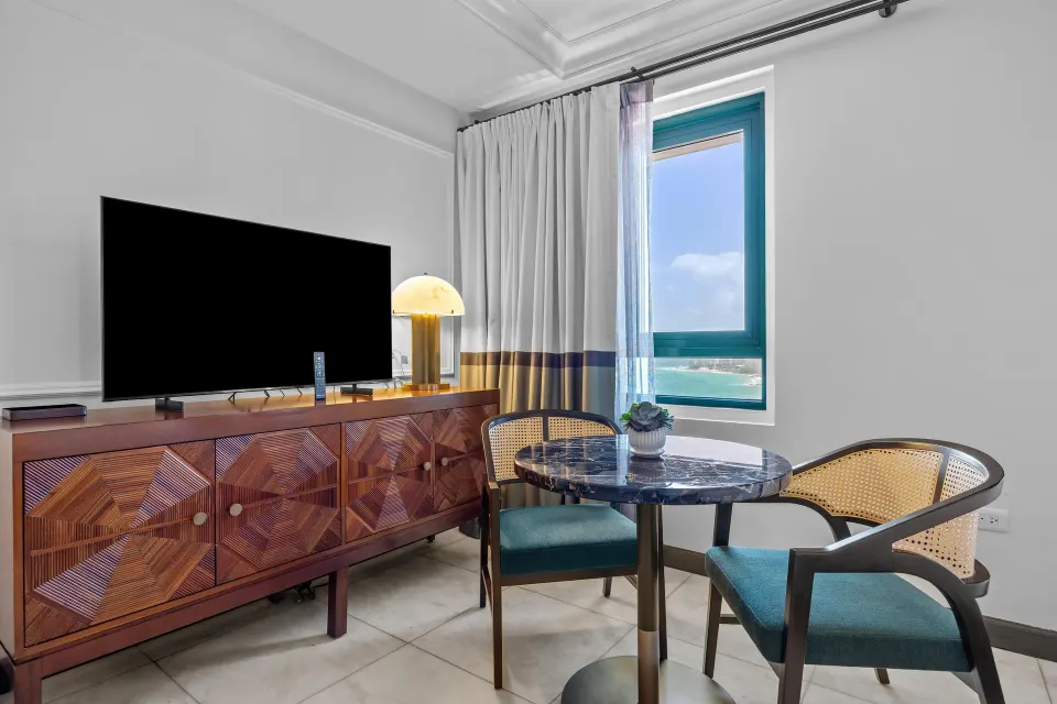 Ocean View Tower King Room seating area with TV console and ocean window at Condado Vanderbilt Hotel.