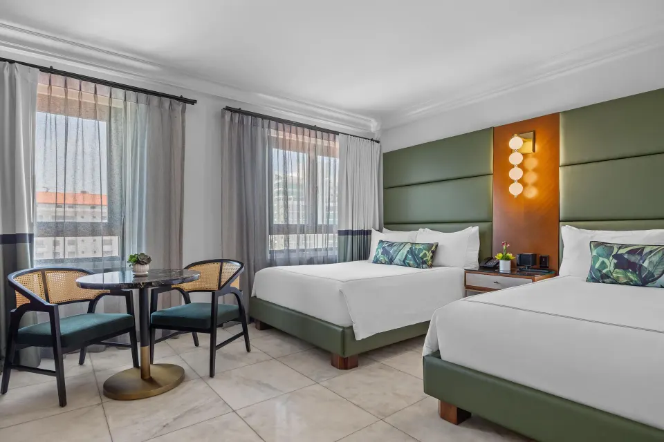Ocean View Tower room with two beds, table seating, and tall windows at Condado Vanderbilt Hotel.