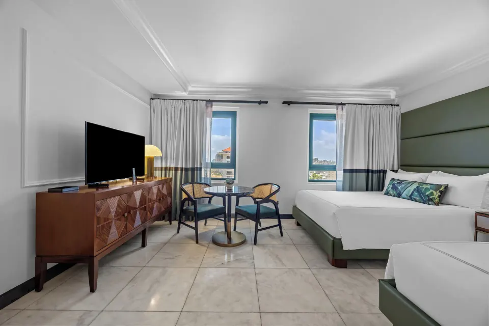 Bright Ocean View Tower Queen Room at Condado Vanderbilt Hotel with TV console, seating, and two queen beds.