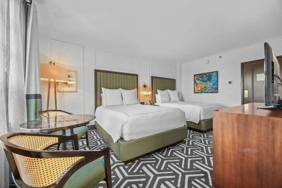 Oceanfront One-Bedroom Room at Condado Vanderbilt Hotel with two beds, patterned carpet, and sitting area.
