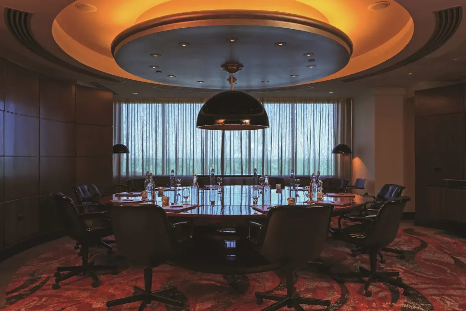Boardroom with oval table and curtain-filtered windows at Condado Vanderbilt Hotel.