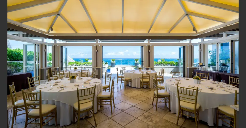 Ocean-view event room with round banquet tables at Condado Vanderbilt Hotel.