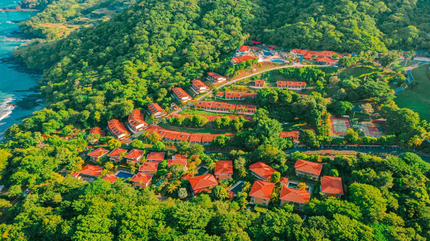 Aerial view of red-roofed villas and forested hills at Condovac la Costa.