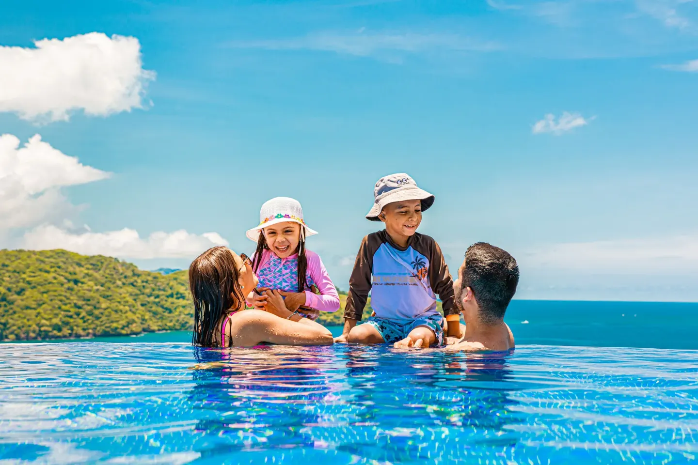 Family playing in the infinity pool with ocean backdrop at Condovac la Costa.