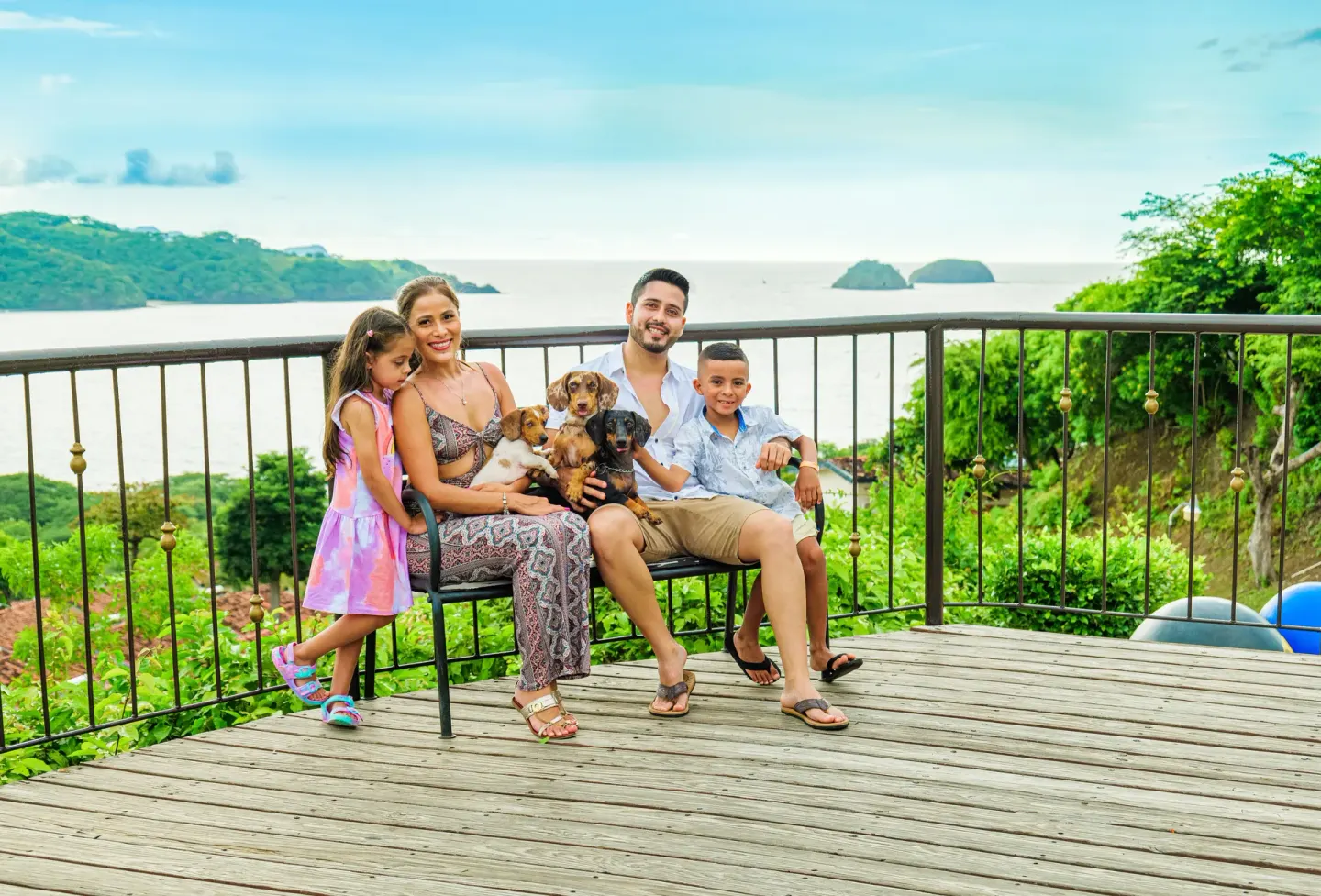 A family with dogs sits on a terrace overlooking the bay at Condovac la Costa.