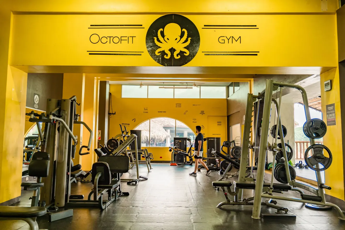 Yellow gym entrance with strength machines and weights at Condovac la Costa.