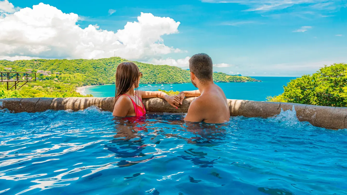 Couple in an infinity pool overlooking the bay at Condovac la Costa.