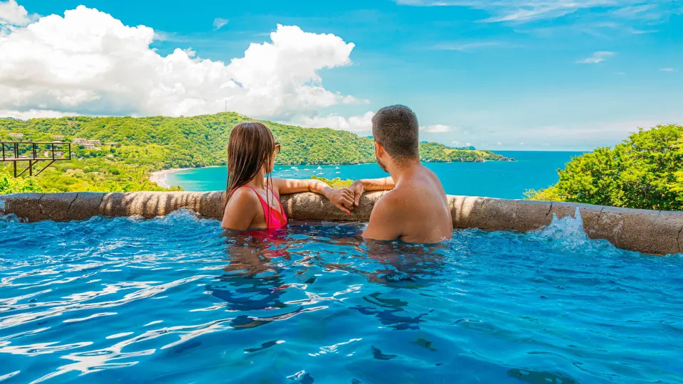 Couple in an infinity pool overlooking the bay at Condovac la Costa.