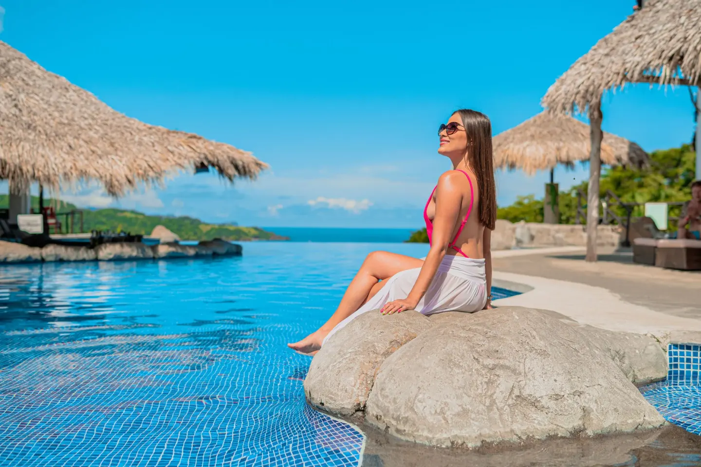 Guest seated on rock feature beside the infinity pool at Condovac la Costa.