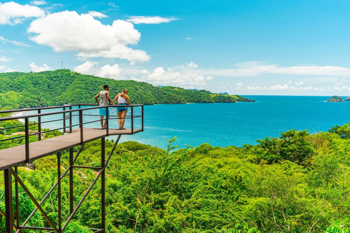 Couple on a lookout platform above the blue bay at Condovac la Costa.