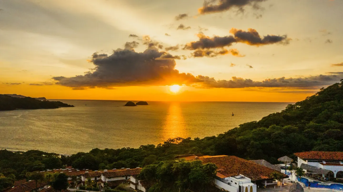 Sunset over the bay, hills, and resort rooftops at Condovac la Costa.