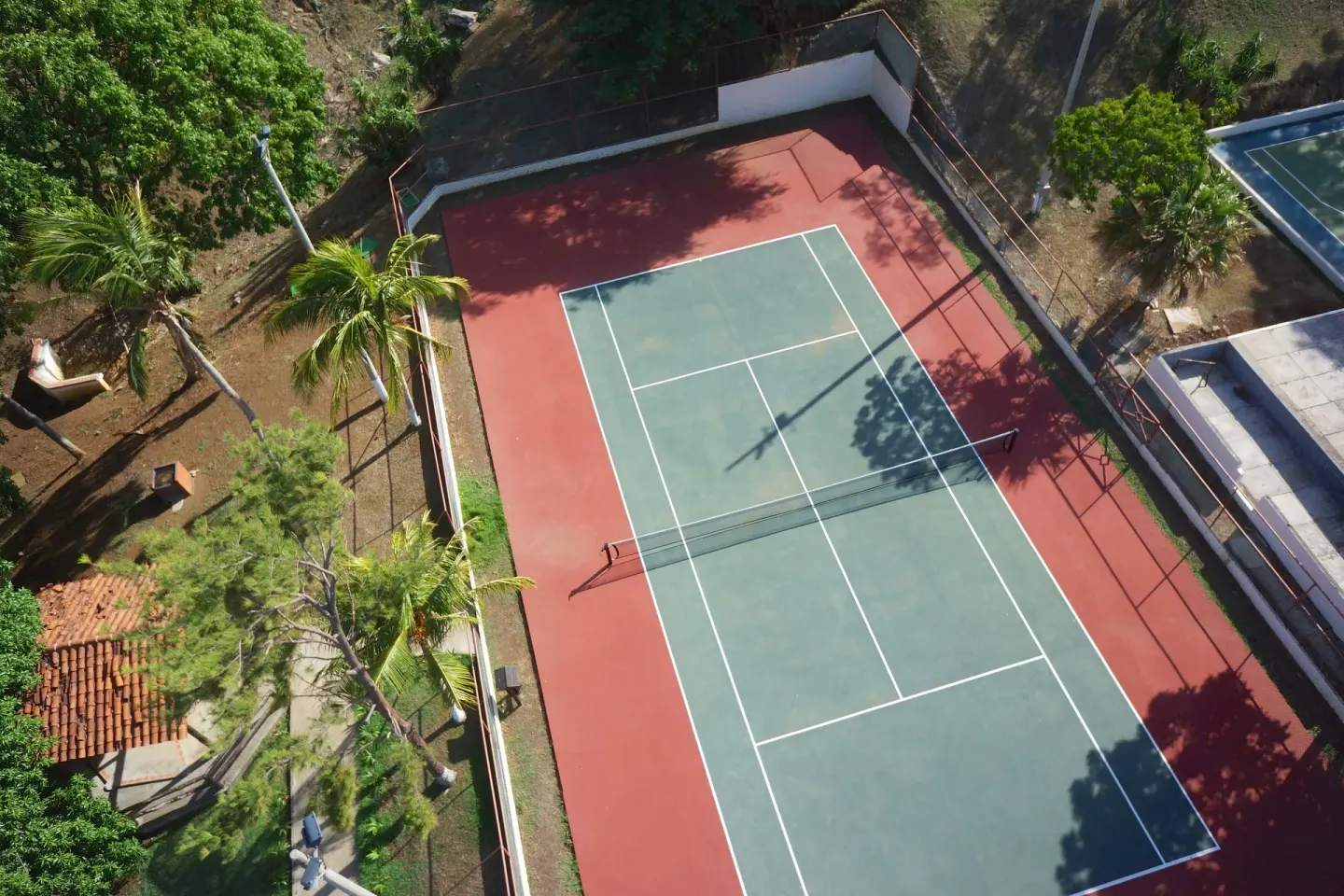 Aerial view of the tennis court surrounded by trees at Condovac la Costa.