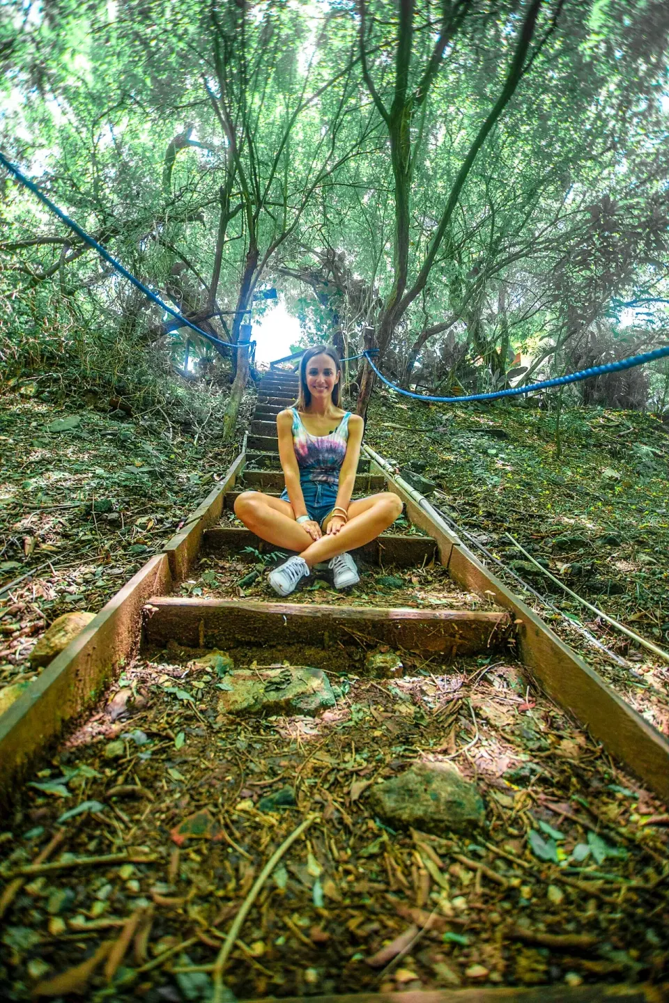 A woman sits on wooded steps along a shaded trail at Condovac la Costa.