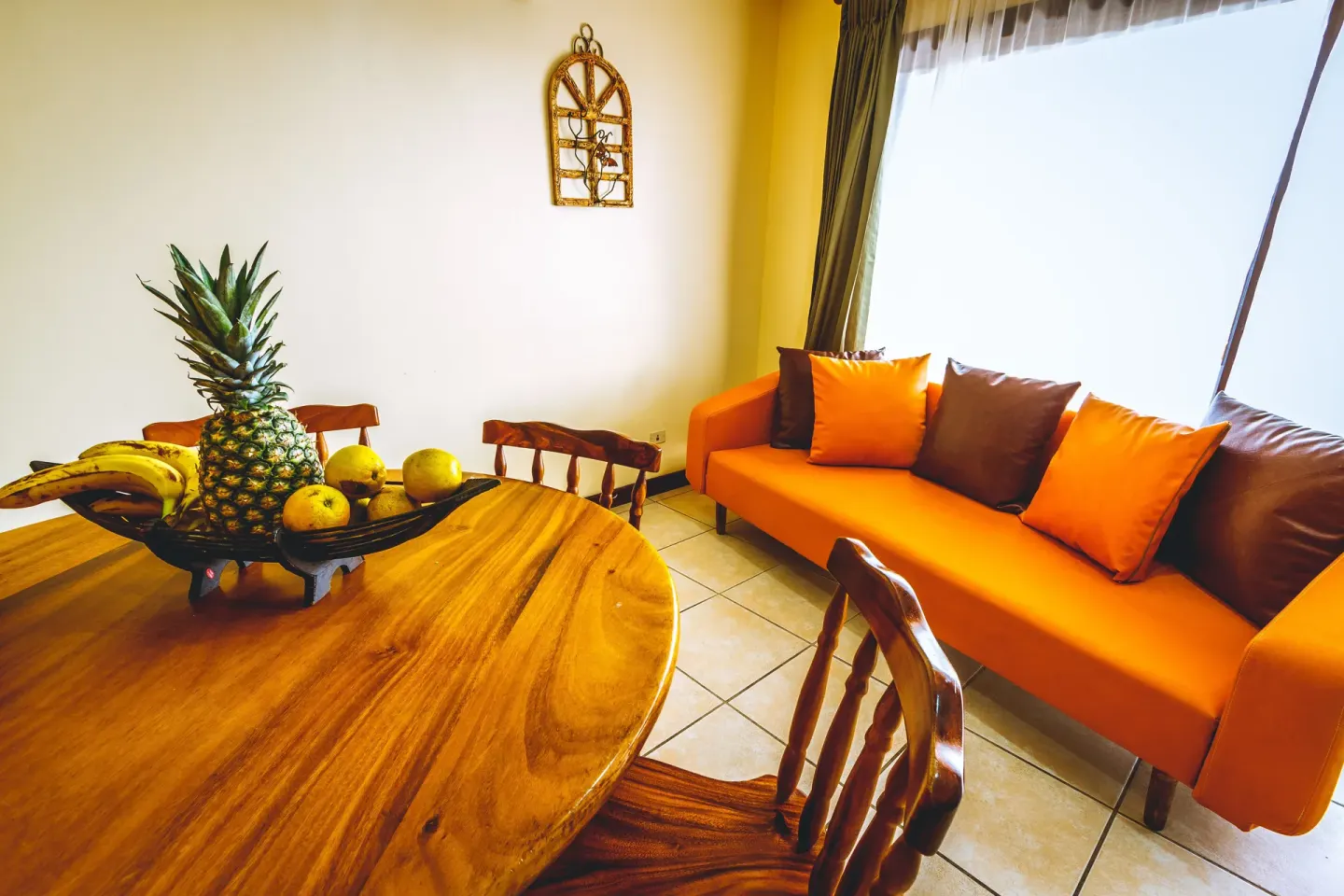 Standard Villa dining nook with orange sofa and wooden table at Condovac la Costa.