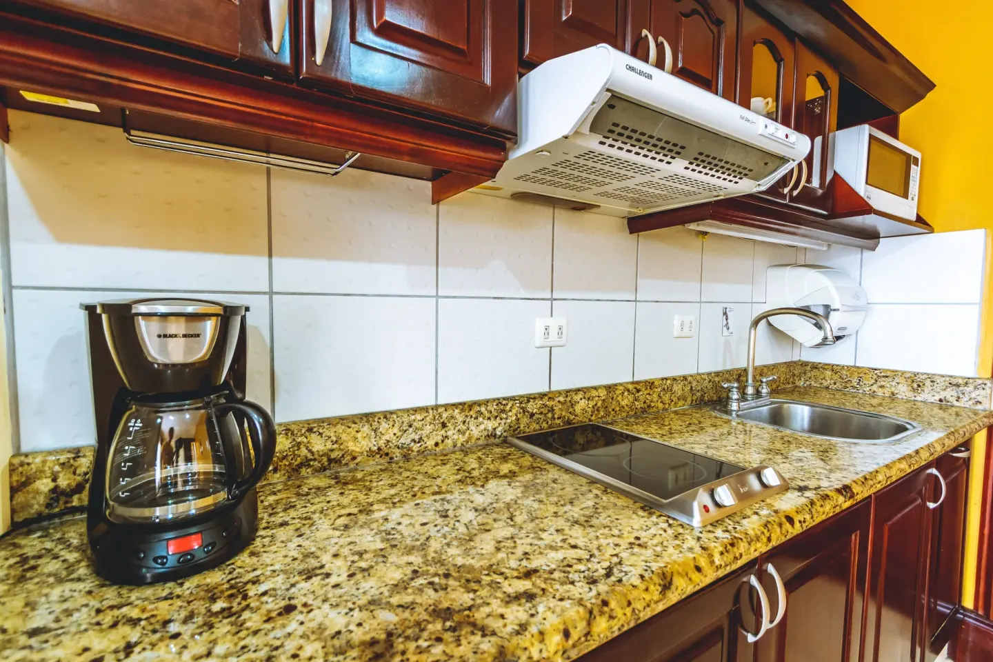 Standard Villa kitchen counter with cooktop, sink, microwave, and coffee maker at Condovac la Costa.
