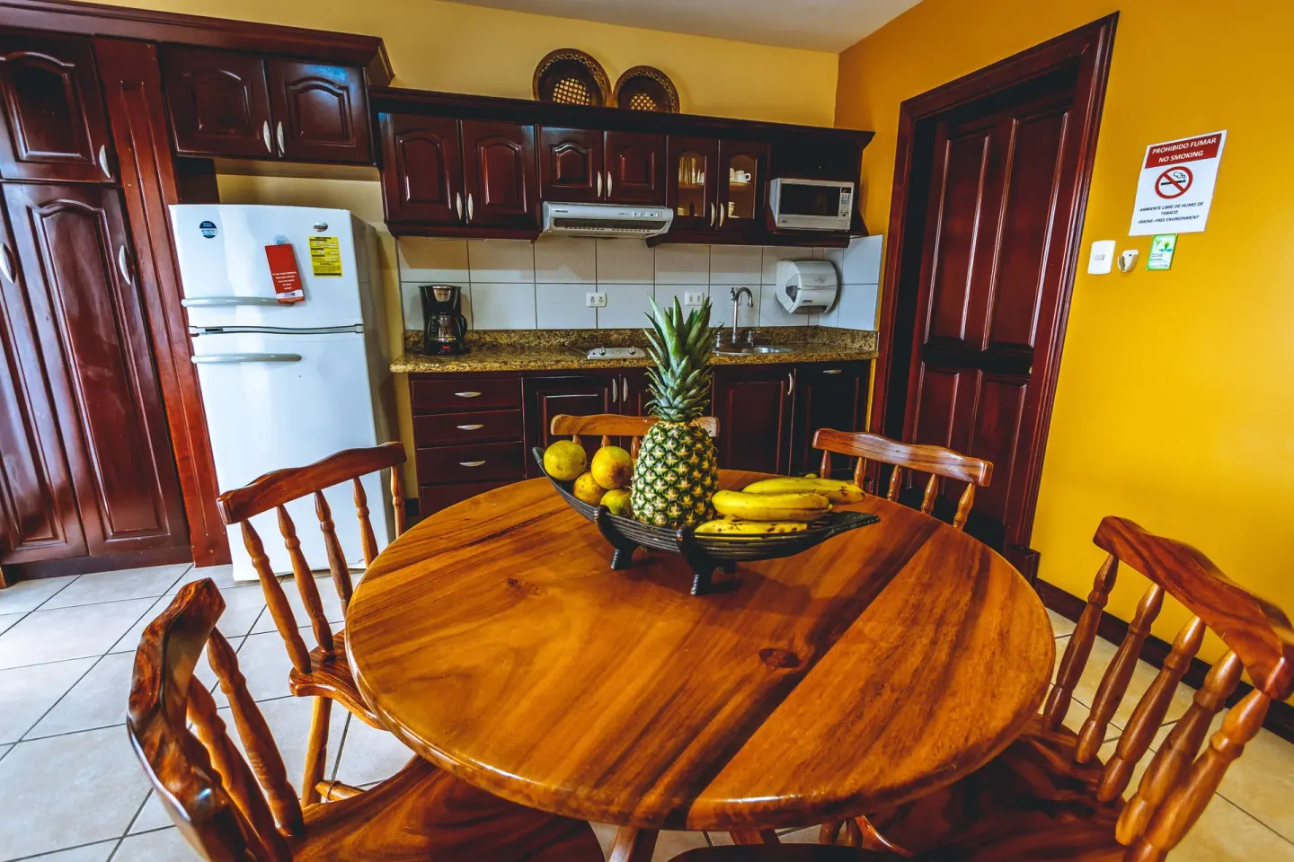 Standard Villa kitchen and dining area with round table and fruit bowl at Condovac la Costa.