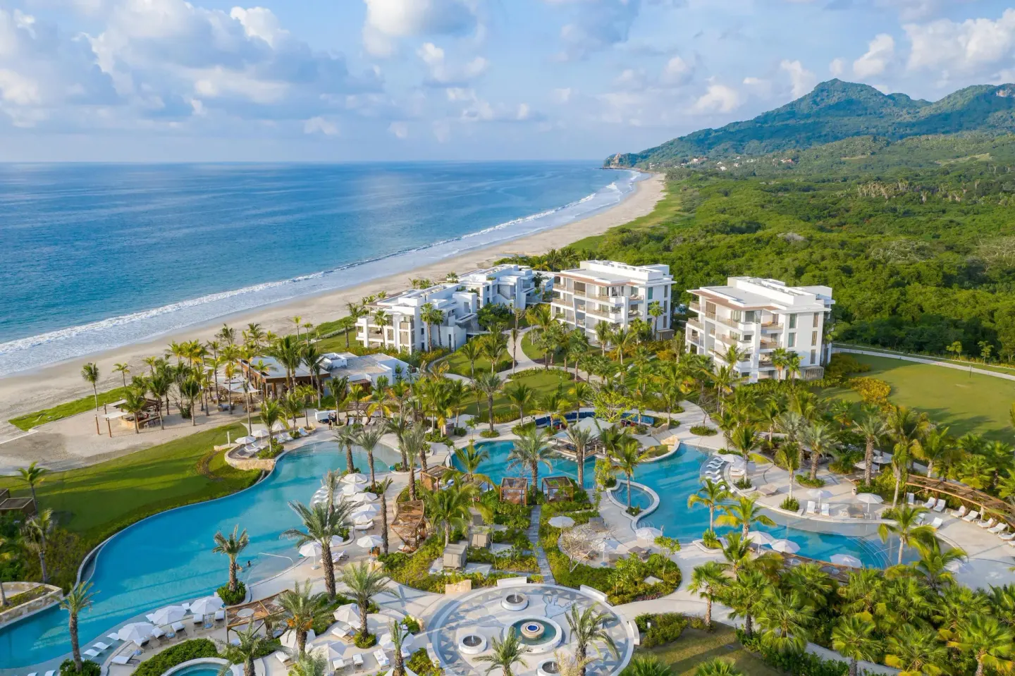 Aerial view of pools, palms, beach, and ocean at Conrad Punta de Mita.