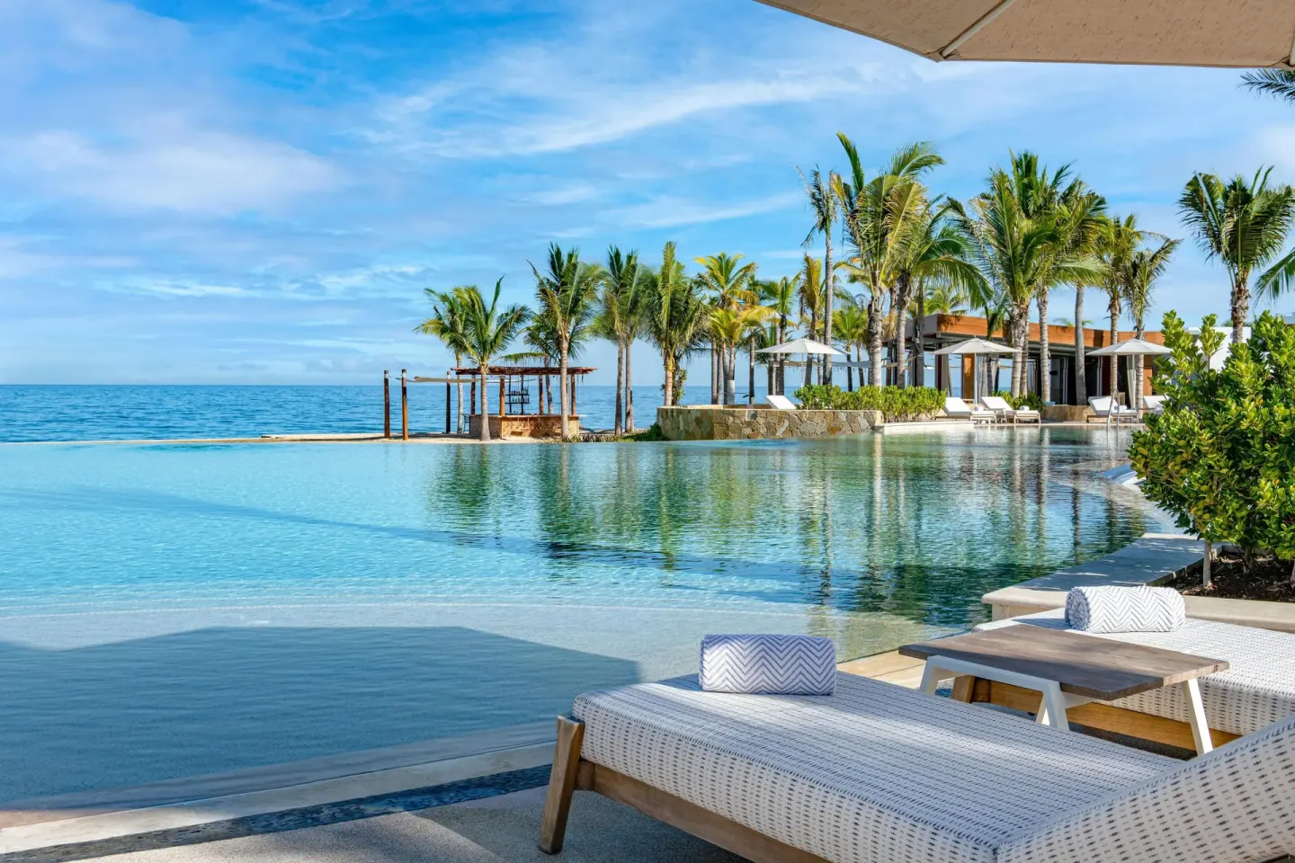 Beachfront pool with loungers, palms, and ocean views at Conrad Punta de Mita.