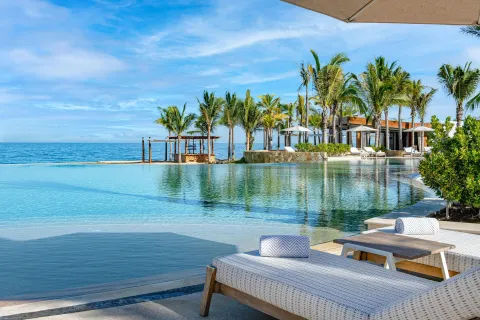 Beachfront pool with loungers, palms, and ocean views at Conrad Punta de Mita.