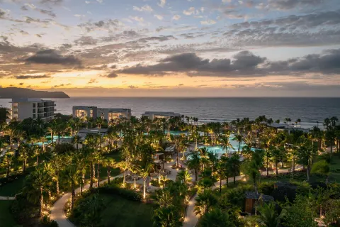 Illuminated resort grounds, pools, palms, and ocean at dusk at Conrad Punta de Mita.