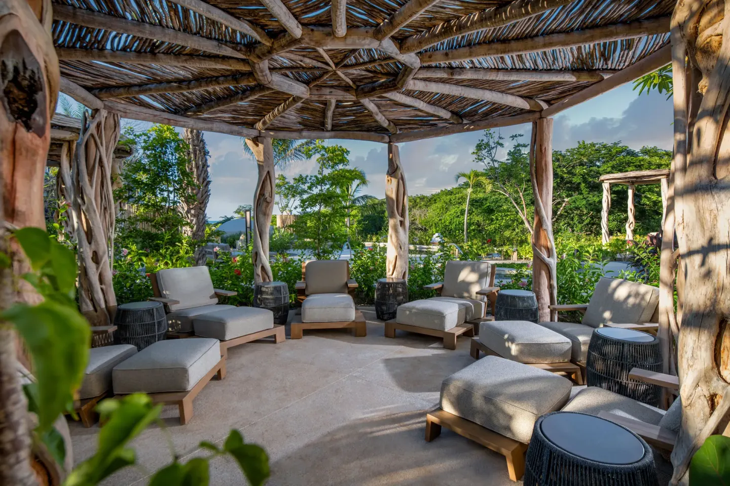 Shaded garden lounge with cushioned chairs and rustic wood posts at Conrad Punta de Mita.