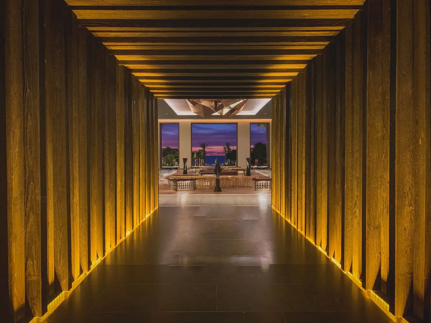 Illuminated wood-lined corridor leading to the lobby at Conrad Punta de Mita.