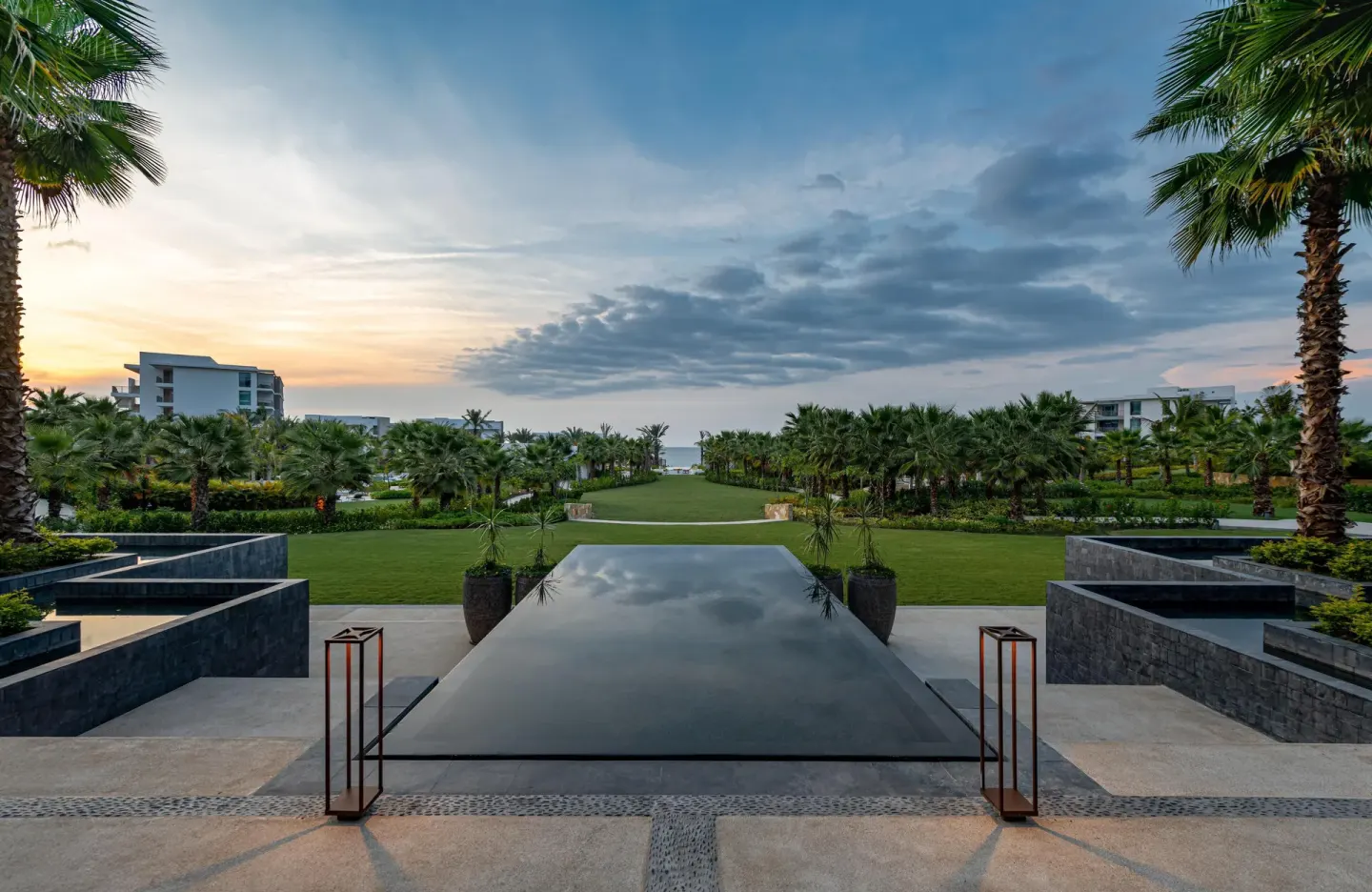 Reflecting pool and palm-lined lawn leading toward the ocean at Conrad Punta de Mita.