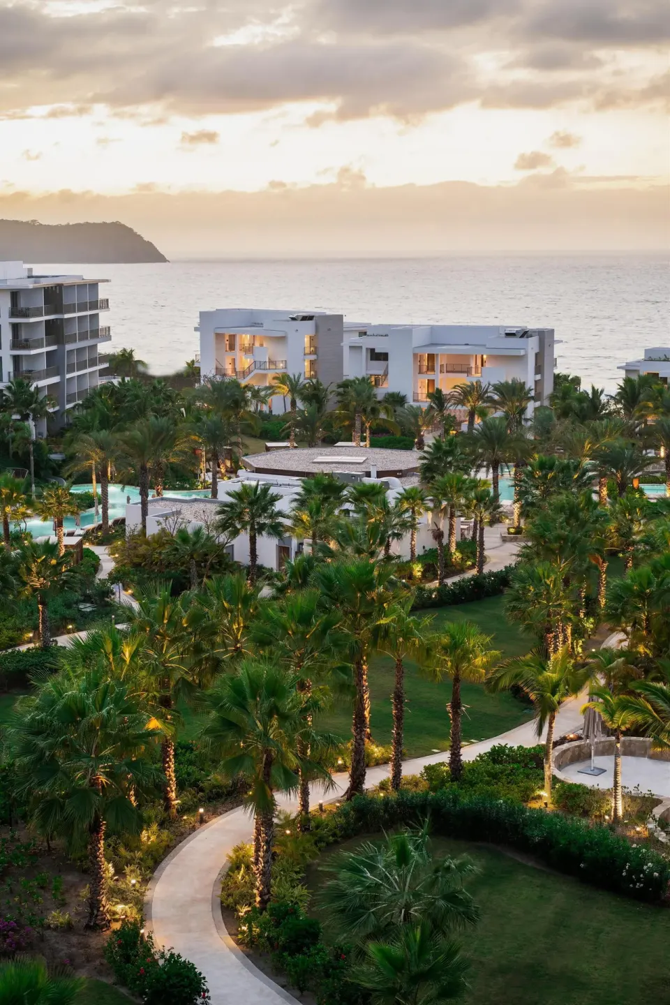 Resort buildings, palms, pools, and ocean at sunset at Conrad Punta de Mita.