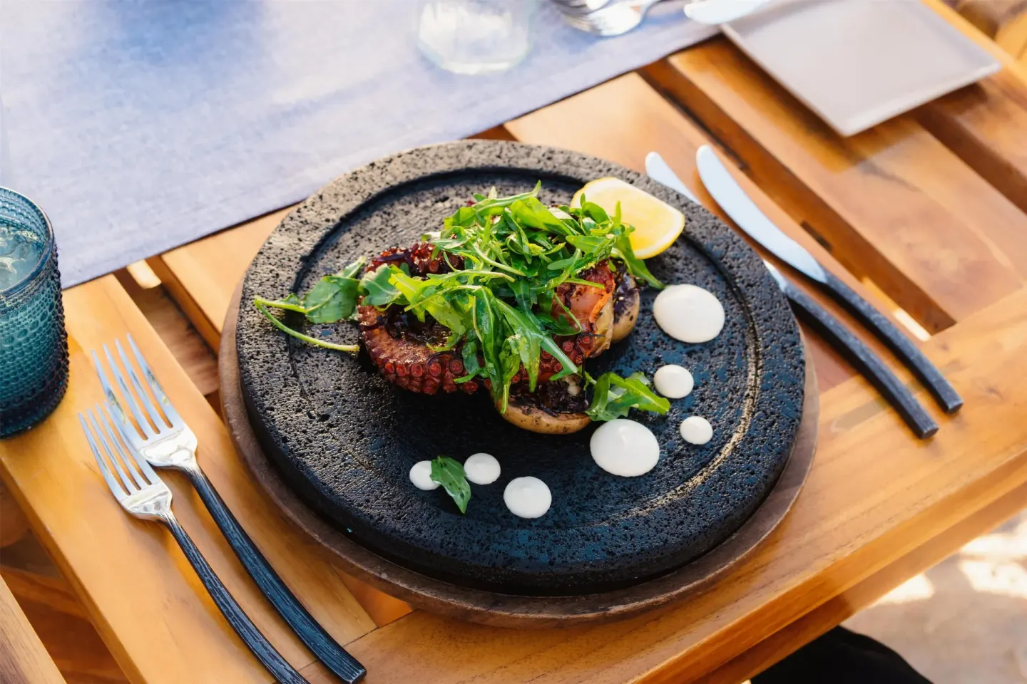 Grilled octopus dish on a black plate at Conrad Punta de Mita.