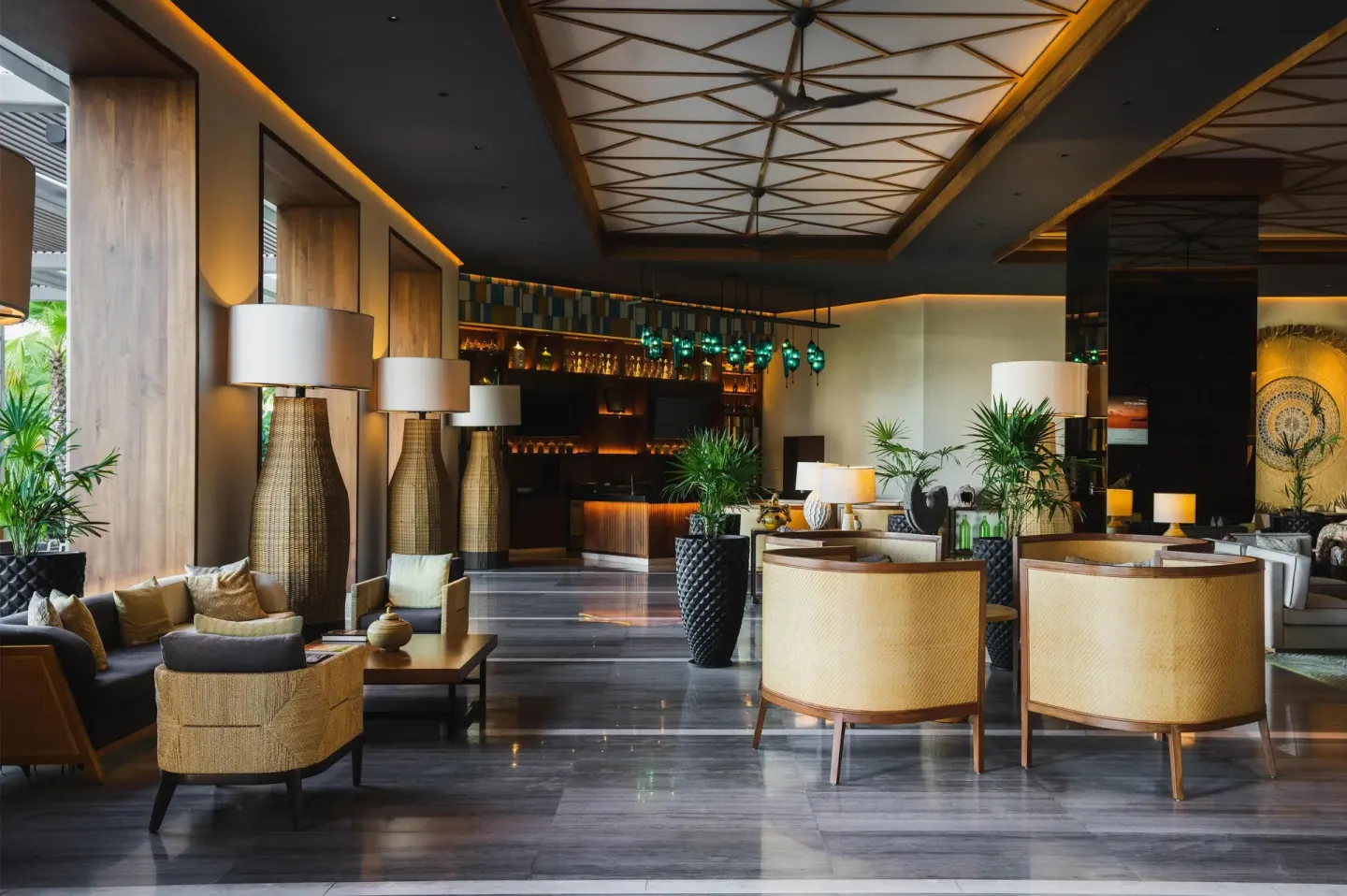 Lounge seating and bar area with woven chairs and plants at Conrad Punta de Mita.
